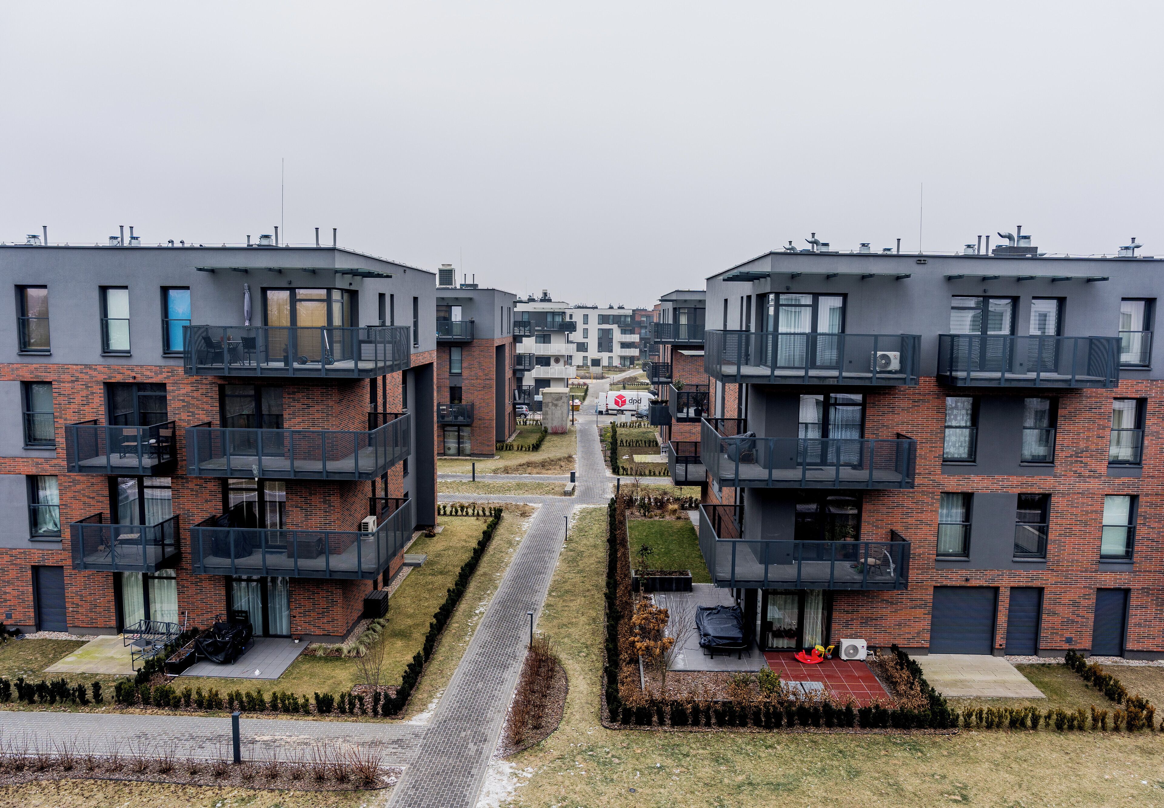 Um complexo de apartamentos moderno com várias varandas, um caminho central e uma pequena área de jardim.