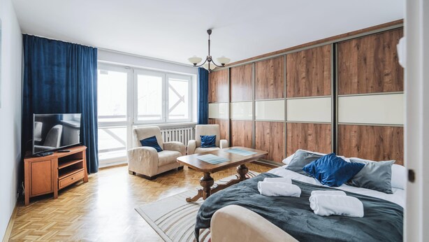 Een moderne hotelkamer met een groot bed, een televisie, een zithoek en uitzicht op het groen.