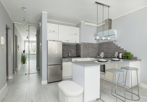 A modern kitchen with white cabinets, a grey countertop, and a brick backsplash. - Szczecin 9 Maja Bright Studio (Szczecin)