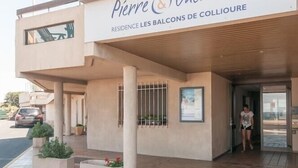 Un hotel llamado "Pierre & Vacances" con un estilo arquitectónico moderno, que presenta una fachada plana, ventanas amplias y un área de entrada con azulejos.