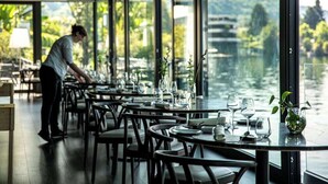 A restaurant with tables set for dining, large windows offering a view of a lake and greenery. - Giardinetto (Pettenasco)