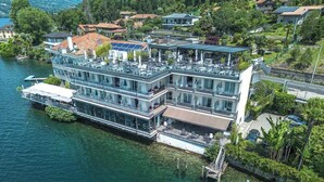 A multi-story waterfront house with balconies, a dock, and a boat. - Giardinetto (Pettenasco)