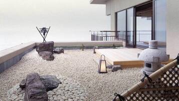 Un jardin sur le toit, doté d’une terrasse en bois, d’un espace salon et d’une lanterne en pierre.