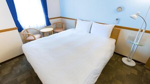 A hotel room with a large bed, a small table, two chairs, a bedside lamp, a clock, and a telephone on the wall. - Toyoko INN Kokura-eki Shinkansen-guchi (Kitakyushu)