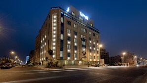 Un hotel de varios pisos con ventanas iluminadas y un cartel llamativo.