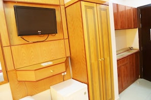 A kitchen with wooden cabinetry, a built-in microwave, and a flat-screen TV mounted above the counter. - Riyadh Al Deafah (Makkah)