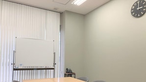 Ein Konferenzraum mit einer Tafel, einer Uhr und einem Telefon.