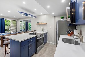 A modern kitchen with a central island, built-in oven, and stainless steel appliances. - New Listing! Modern Garden Oasis in West Maui (Honokowai)