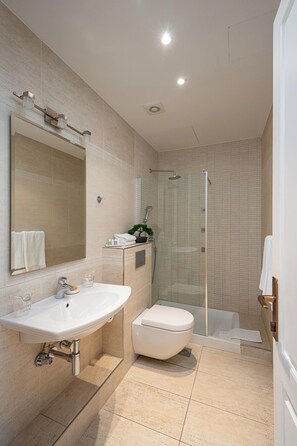 A modern bathroom with a large mirror, a sink, a toilet, and a shower area. - Olea (Dubrovnik)