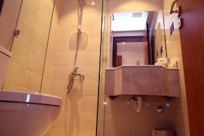 A bathroom with a toilet, a shower, and a sink with a mirror. - Al Bostan Al Masi Hotel (Makkah)