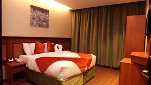 A hotel room with a bed, a nightstand, a desk, and a curtain. - Al Bostan Al Masi Hotel (Makkah)