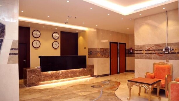 A lobby with a reception desk, a flat-screen TV, a coffee table, and seating area with chairs. - Al Bostan Al Masi Hotel (Makkah)