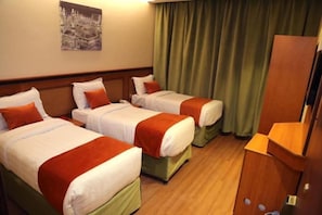 A hotel room with two beds, a wooden headboard, a green curtain, and a wooden desk. - Al Bostan Al Masi Hotel (Makkah)