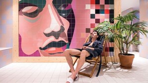A person sitting in a chair with a large abstract painting in the background. - St. Martenslane Hotel Maastricht (Maastricht)