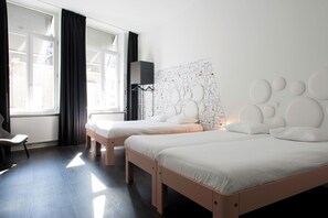 A hotel room with two beds, a large window with curtains, a radiator, and a wall with a geometric pattern. - Mabi Hotel Centrum (Maastricht)