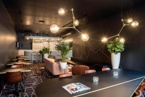 A modern restaurant with a dark interior, geometric patterned floor, and a central seating area with a round table. - Mabi Hotel Centrum (Maastricht)