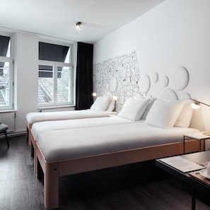 A modern hotel room with a large bed, bedside tables, a desk, and a view of the cityscape through the window. - Mabi Hotel Centrum (Maastricht)
