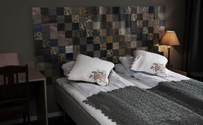 Uma cama bem arrumada com almofadas florais, cabeceira acolchoada e abajur.
