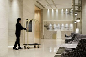 A modern lobby with a reception desk, seating area, and a person pushing a cart. - Courtyard By Marriott Osaka Honmachi (Osaka)