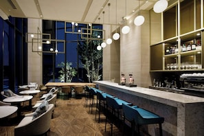 A modern bar area with a marble countertop, bar stools, and a variety of bottles and glasses. - Courtyard By Marriott Osaka Honmachi (Osaka)
