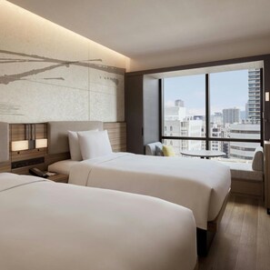 A hotel room with two beds, a large window with a city view, a bedside table with a lamp, and a headboard with a painting. - Courtyard BY Marriott Osaka Honmachi (Osaka)