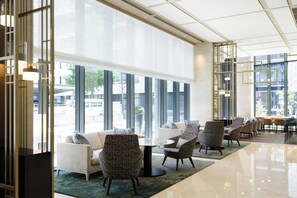 A modern hotel lobby with large windows, a seating area with sofas and chairs, and a central table. - Courtyard By Marriott Osaka Honmachi (Osaka)