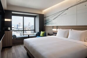 A modern hotel room with a large bed, a seating area with a view of the city, and a large window. - Courtyard BY Marriott Osaka Honmachi (Osaka)