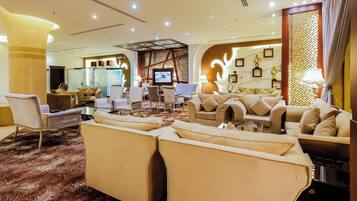 A spacious lobby with multiple seating areas, a television, and a decorative wall.