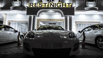 A luxury car dealership with a prominent 'REST NIGHT' sign, showcasing a white sports car with a visible license plate.