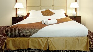 A neatly made bed with a patterned bedspread, two bedside lamps, and a decorative headboard. - Rest Night Hotel Suites Al Hamra (Riyadh)