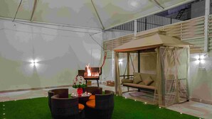A tented outdoor area with a fire pit, wicker furniture, and a cushioned seating area. - Rest Night Hotel Suites Al Hamra (Riyadh)