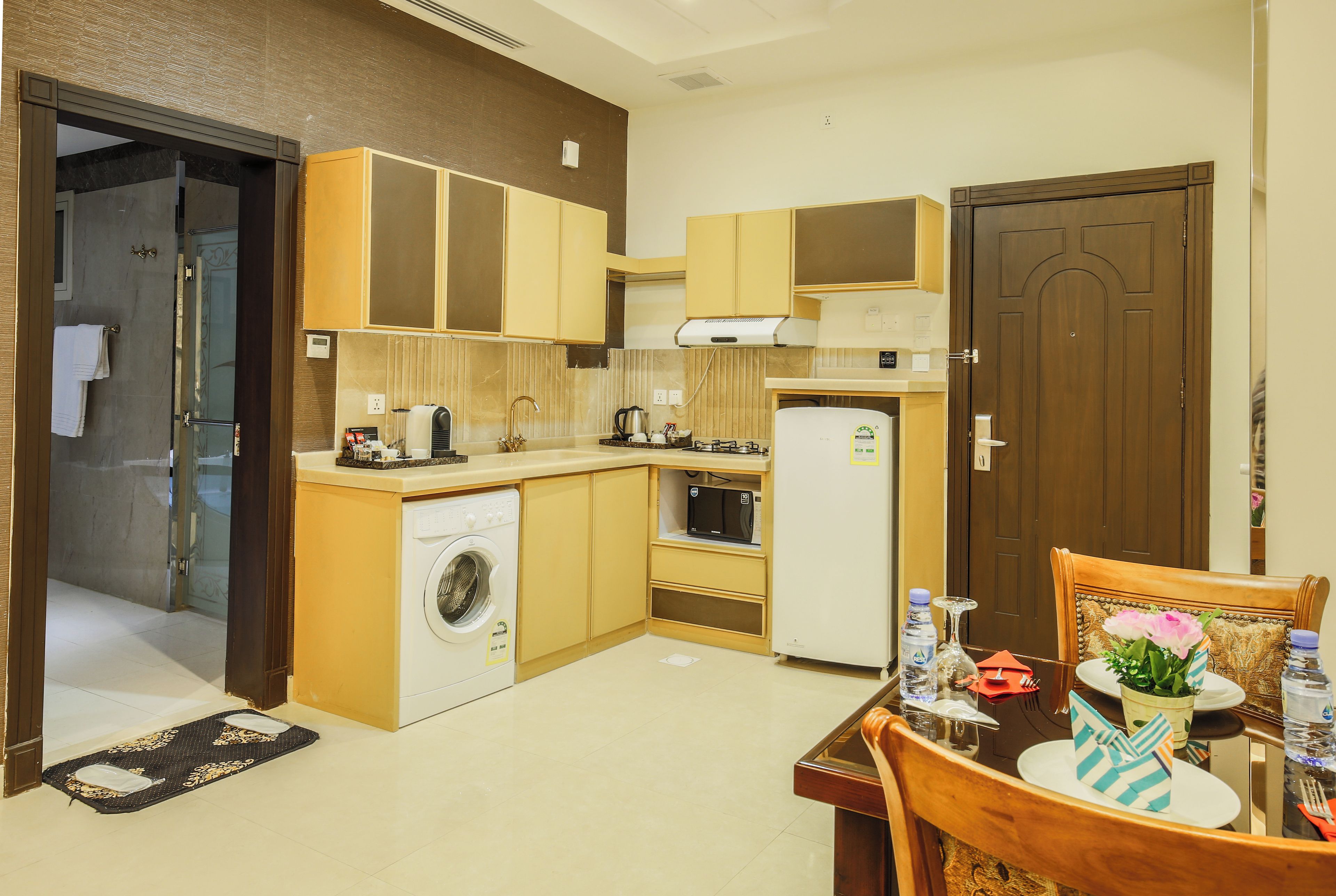 A compact kitchen with a washing machine, microwave, and refrigerator.