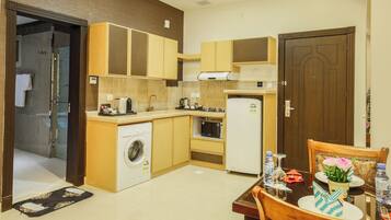 A compact kitchen with a washing machine, microwave, and refrigerator.