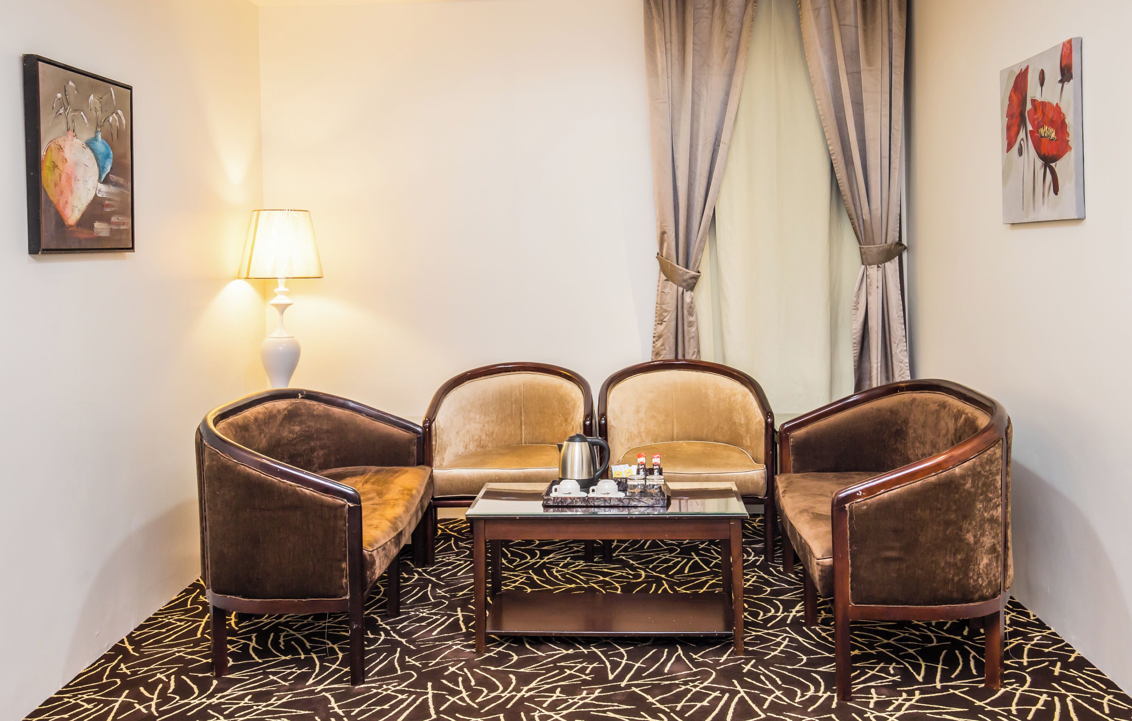 A room with a sofa set, two armchairs, a coffee table, and a lamp.