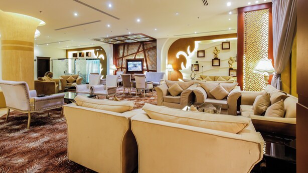 A spacious lobby with multiple seating areas, a television, and a decorative wall. - Rest Night Hotel Suites Al Hamra (Riyadh)