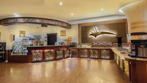 A coffee shop with a curved counter, a coffee machine, and various coffee cups and pastries. - Rest Night Hotel Suites Al Hamra (Riyadh)