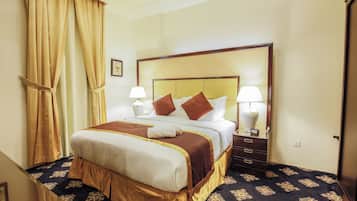 A hotel room with a large bed, two bedside tables with lamps, a wooden headboard, and a patterned carpet.