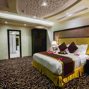 Una habitación de hotel con una cama grande, una mesita de noche, una lámpara y un techo decorativo.