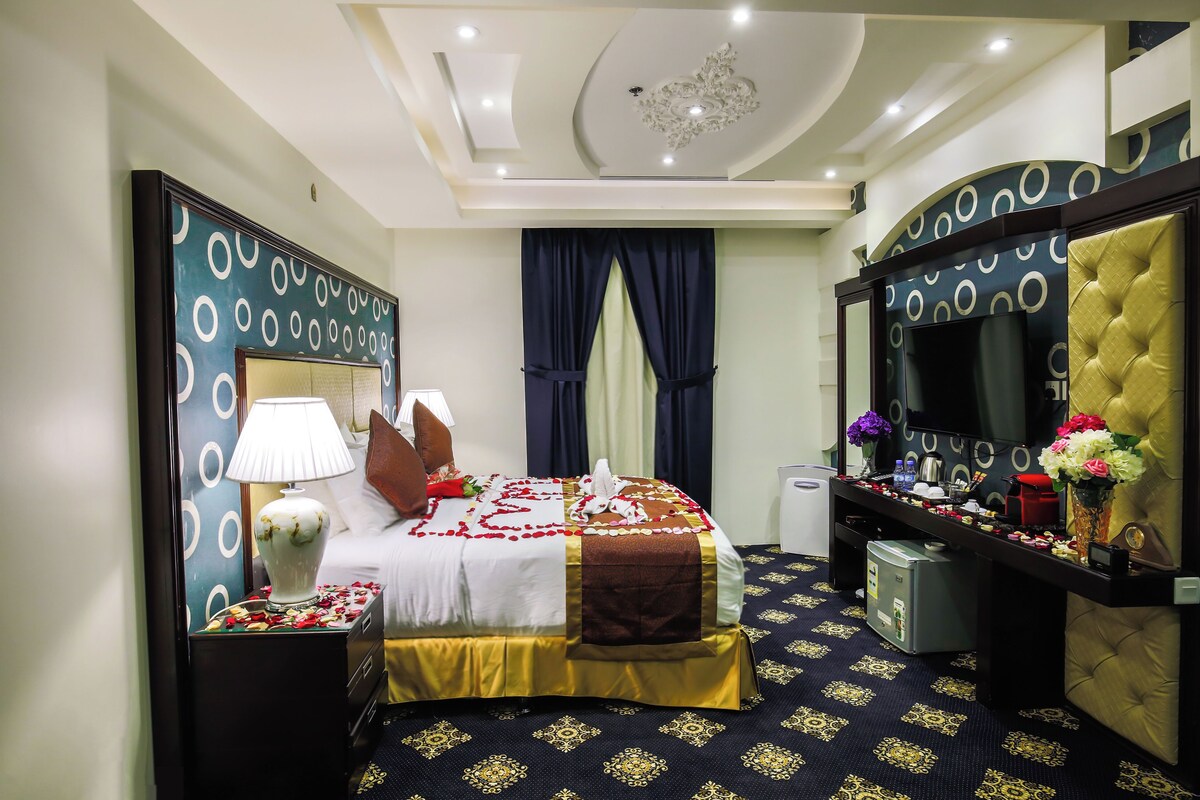 A hotel room with a bed, bedside table, lamp, and a mirror.