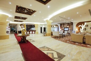 A spacious lobby with a red carpet, a reception desk, and a seating area with sofas and chairs. - Rest Night Hotel Suites Al Hamra (Riyadh)