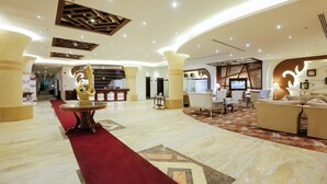 A spacious lobby with a red carpet, a reception desk, and a seating area with sofas and chairs. - Rest Night Hotel Suites Al Hamra (Riyadh)