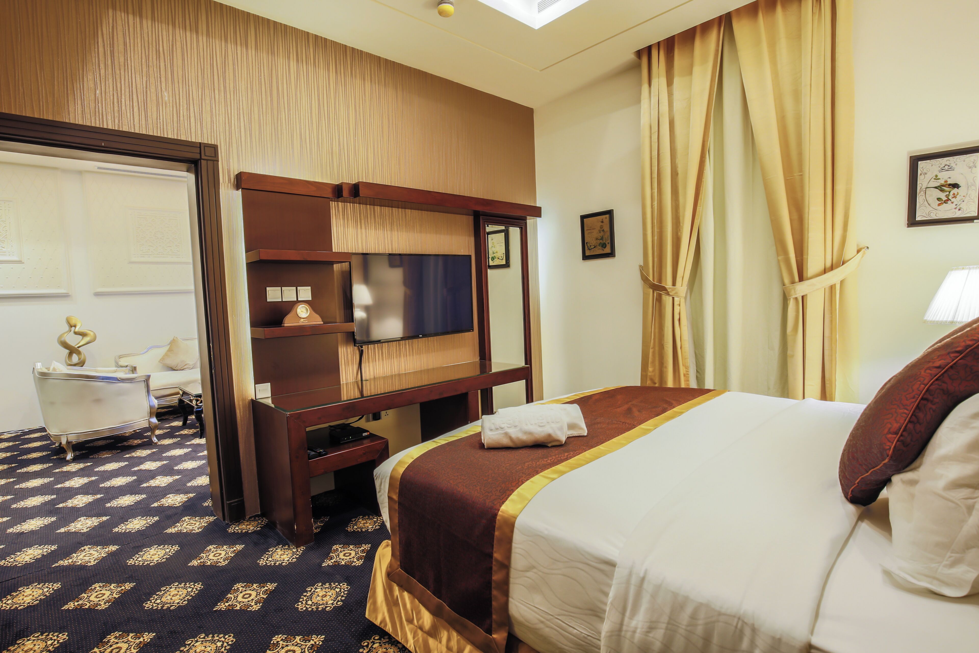 A hotel room with a bed, a desk, a television, and a wardrobe.