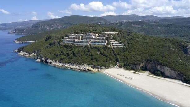 A coastal hotel with multiple buildings, a beach, and a mountainous backdrop. - Marbella Elix (Igoumenitsa)