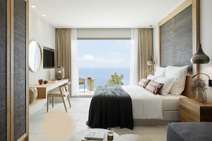Una habitación de hotel moderna con cama, escritorio, silla y vista al mar.