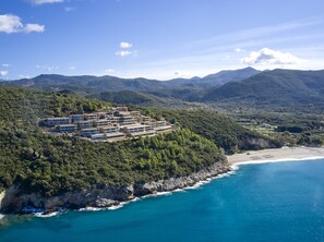 A coastal resort with multiple buildings, a beach, and mountainous terrain in the background. - Marbella Elix (Igoumenitsa)