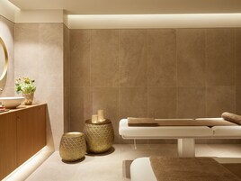 Un baño moderno con un espejo grande, un lavabo, un banco y jarrones decorativos.