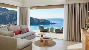 A spacious living room with a large window offering a scenic view of a coastline. - Marbella Elix (Igoumenitsa)
