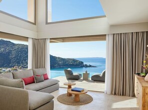 A spacious living room with a large window offering a scenic view of a coastline. - Marbella Elix (Igoumenitsa)