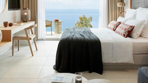 A modern bedroom with a bed, a desk, a chair, a TV, and a view of the sea. - Marbella Elix (Igoumenitsa)