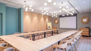 A conference room with a long table, chairs, a projector screen, and a whiteboard. - Ibis Pontivy (Pontivy)